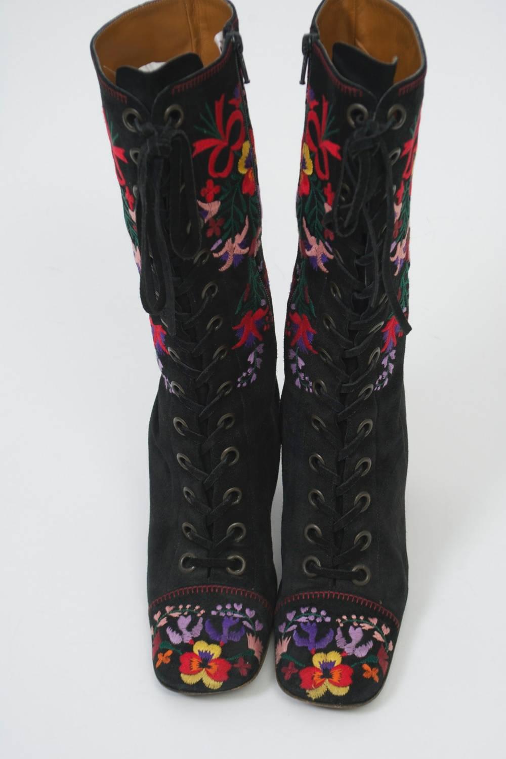 Black suede boots with multicolored embroidered on legs and toe cap. Mid-calf length with thick heel. Inside zipper with front faux laces. Tan leather interior.