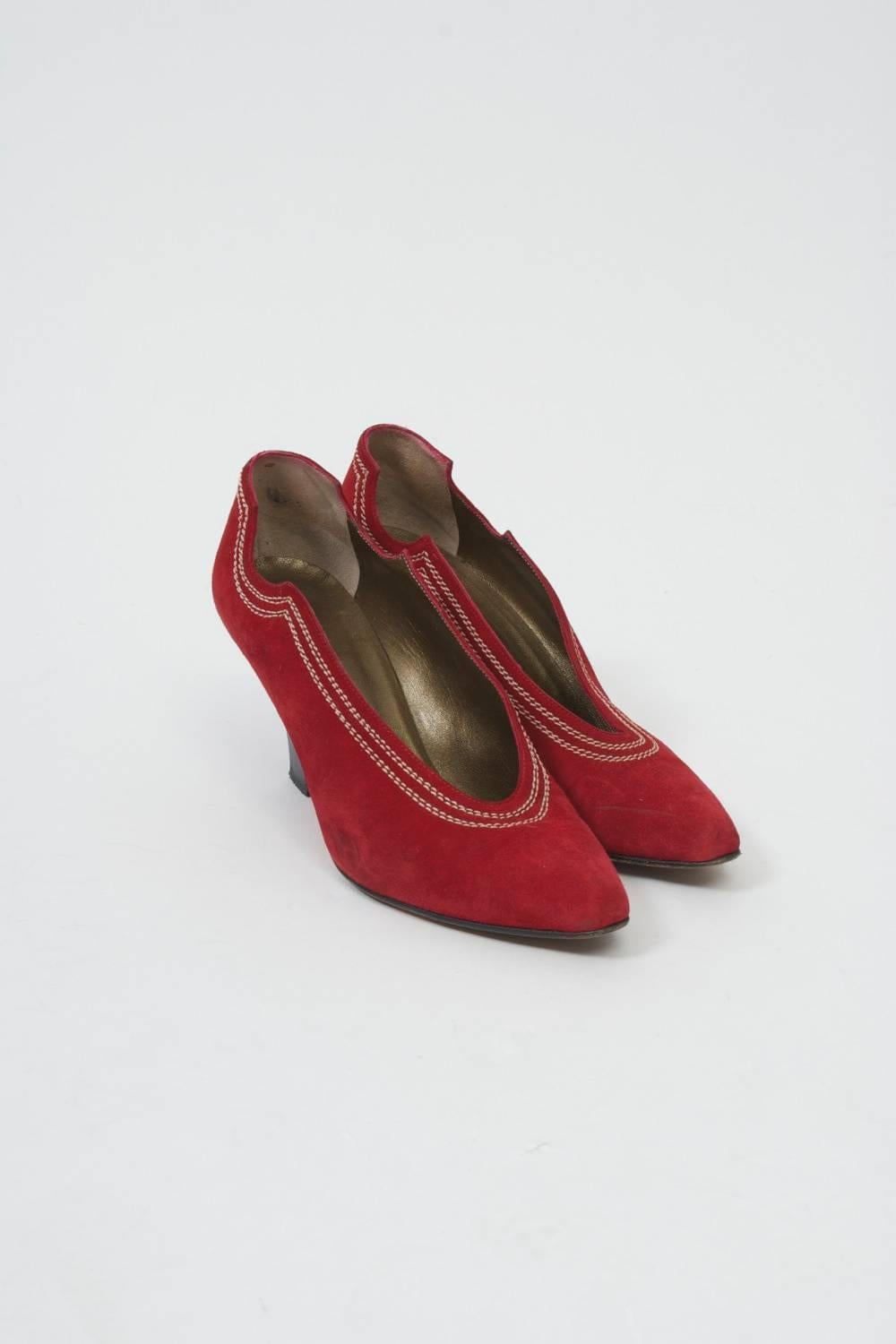 Red suede YSL pumps featuring a double row of white stitching and half-circle cutouts near ankle, an oval instep and black heel. Classic with a twist.