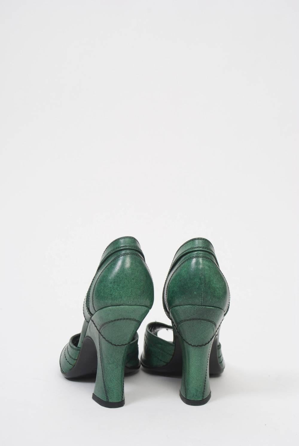D'Orsay pumps in a soft shade of green leather from Prada feature peep toes, spool heels, and black decorative stitching throughout, as well as contoured slits on the sides of the heel backs. No signs of wear.
