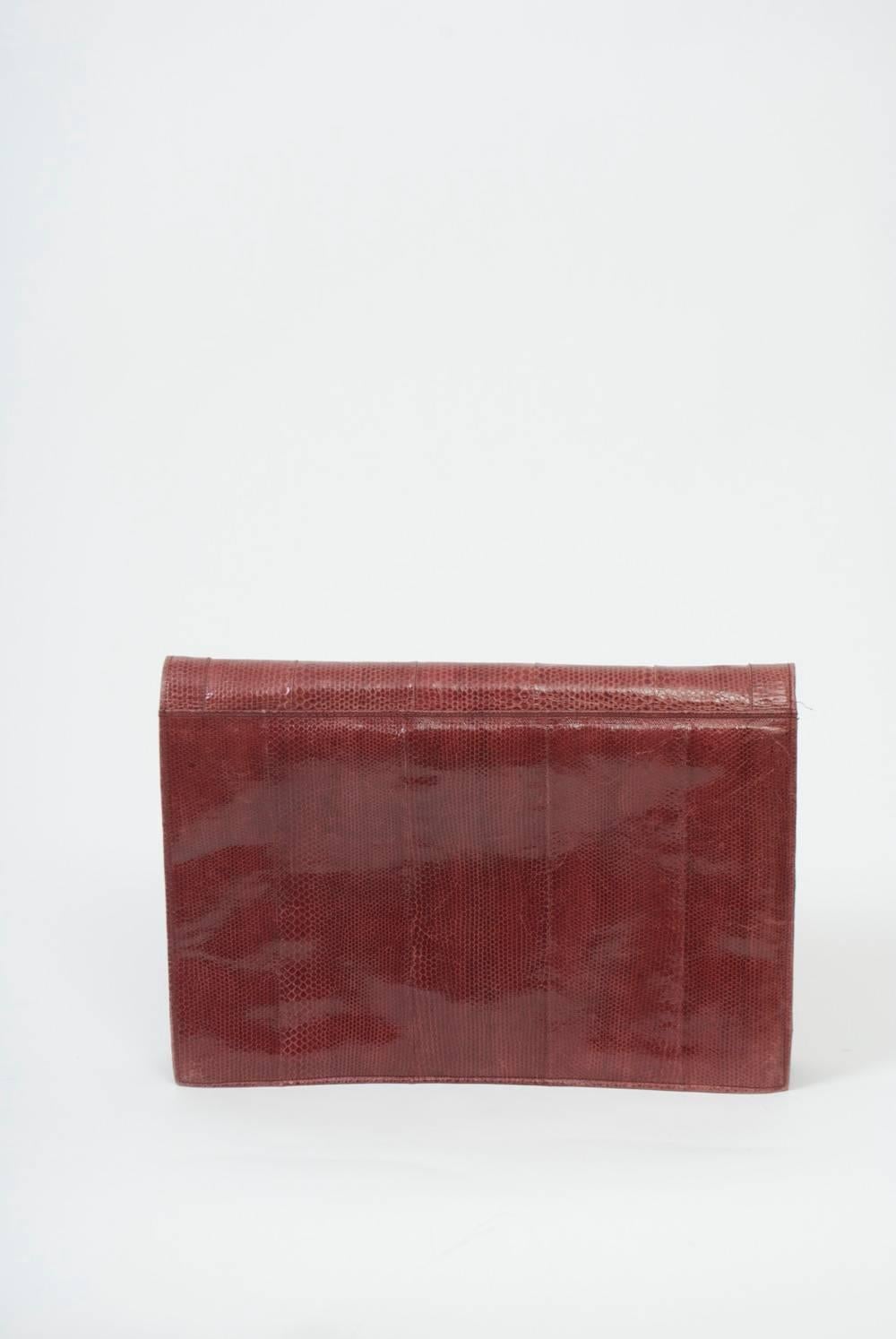 Large envelope clutch in rose snakeskin that opens to reveal two pockets with snaps closures and a gray suede interior with three sections and two zippered compartments on the reverse of the envelope flap. Roomy for work or personal use.