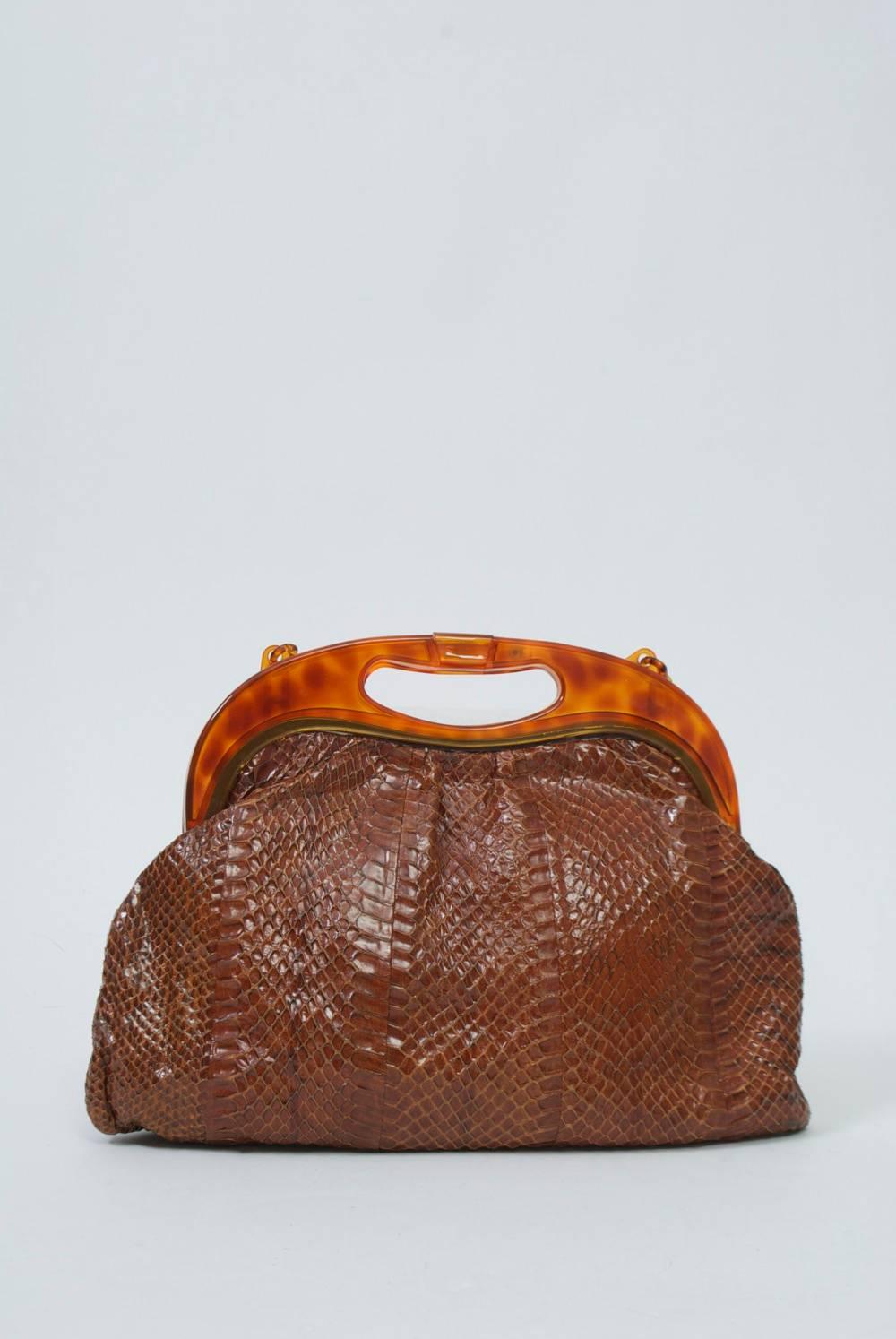 1970s light brown snakeskin handbag featuring a plastic frame, latch, and link shoulder strap in faux tortoise. Soft shape. Interior has zippered compartment on one side. 
