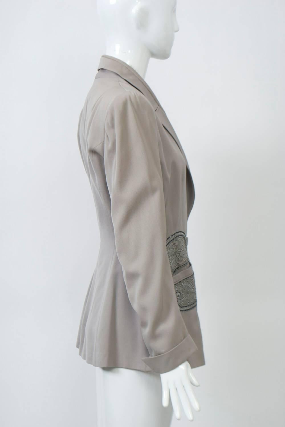 1940s pale taupe gabardine jacket accented with gray beading above and below pockets. Long, fitted body, nipped at waist, with nice detailing, including notched shawl collar, turned-back wrists and single-button closure. Square shoulders with pads.