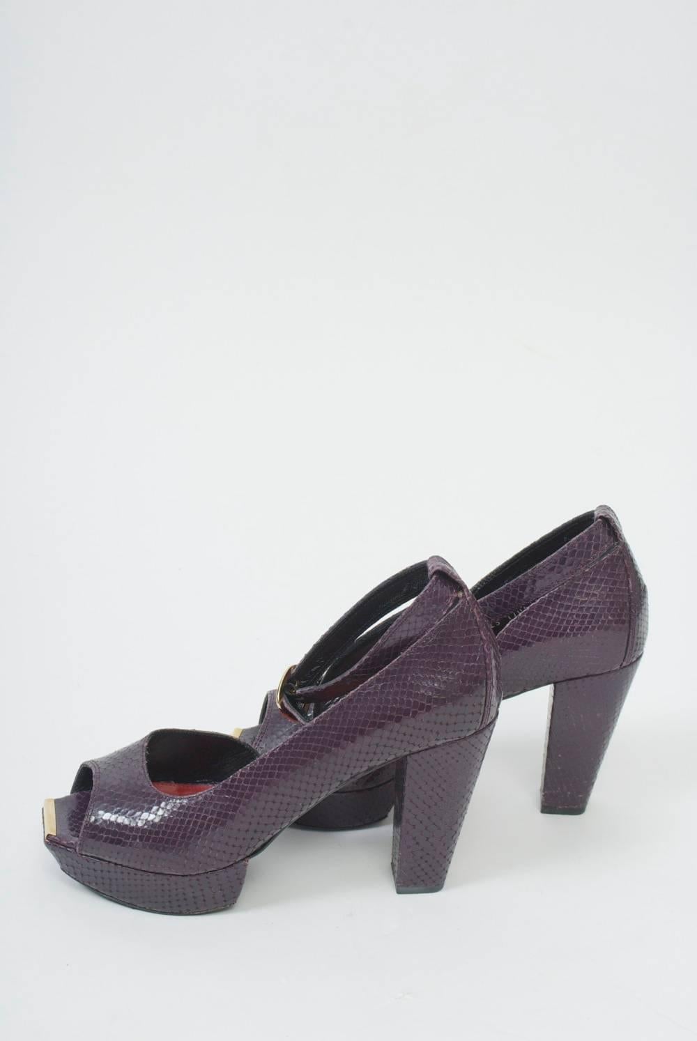Open-toe platform shoes in plum-colored snakeskin by Robert Clergerie featuring ankle straps, a thick high heel and gold bars under the toes. Retailed by Barney's. The shoes show minimal wear.
