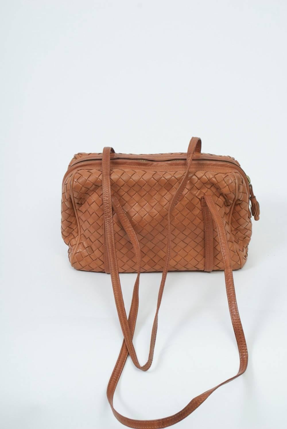 Double-strap luggage shoulder bag in its signature woven leather by Bottega Veneta. Satchel style with soft body and narrow straps that encircle the bag. Long zipper across top and zippered compartment on interior with logo plate.