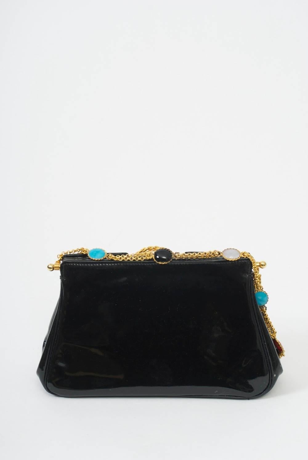 Another unique handbag from Parisian purveyor A La Reine des Fées, this example in black patent featuring a round gold clasp and chain shoulder strap decorated with enameled components in red, black, and turquoise. Lift the clasp to open the bag and