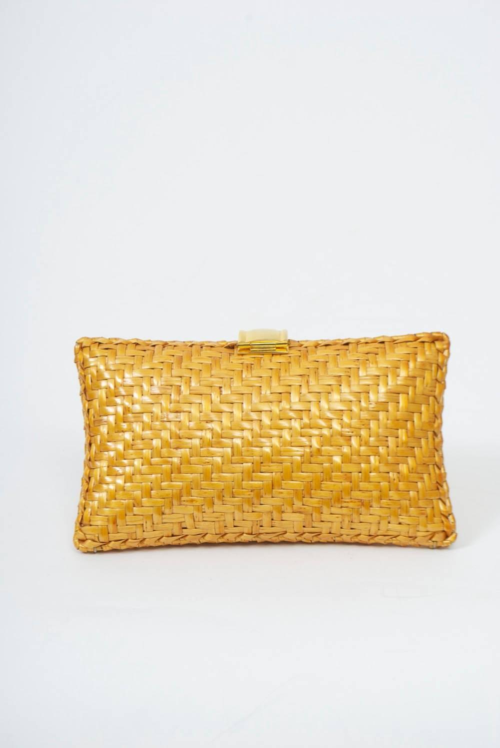 Sleek woven straw clutch with simple gold metal tongue clasp. Interior has a slit side pocket. 