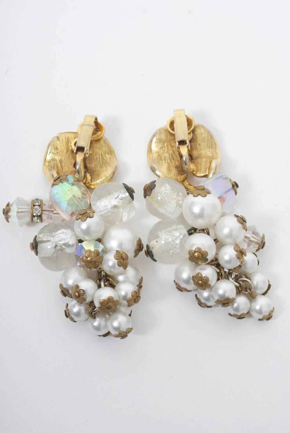 Vintage clip-on earrings composed of a cascade of small pearls, which forms a cluster of grapes that is suspended from a gold metal leaf-form earpiece Additional crystal beads enrich the top of the cluster. Unsigned, but very well executed, and look