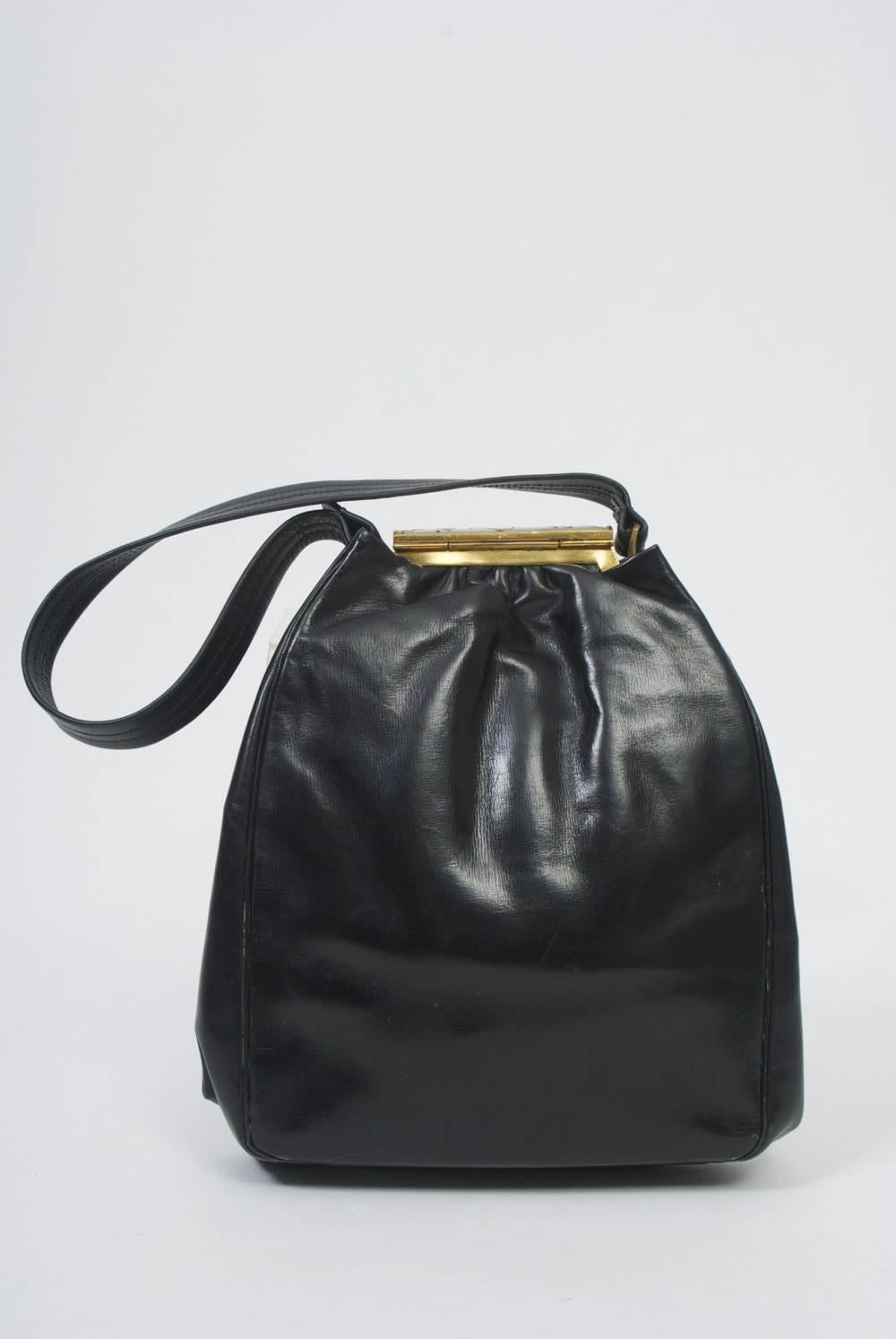 Rosenfeld produced some of the best vintage handbags in America. This example has a black leather body gathered at top where it features a MOP roll bar clasp handpainted with small flowers. Interior is clean with side compartment. Handle has been