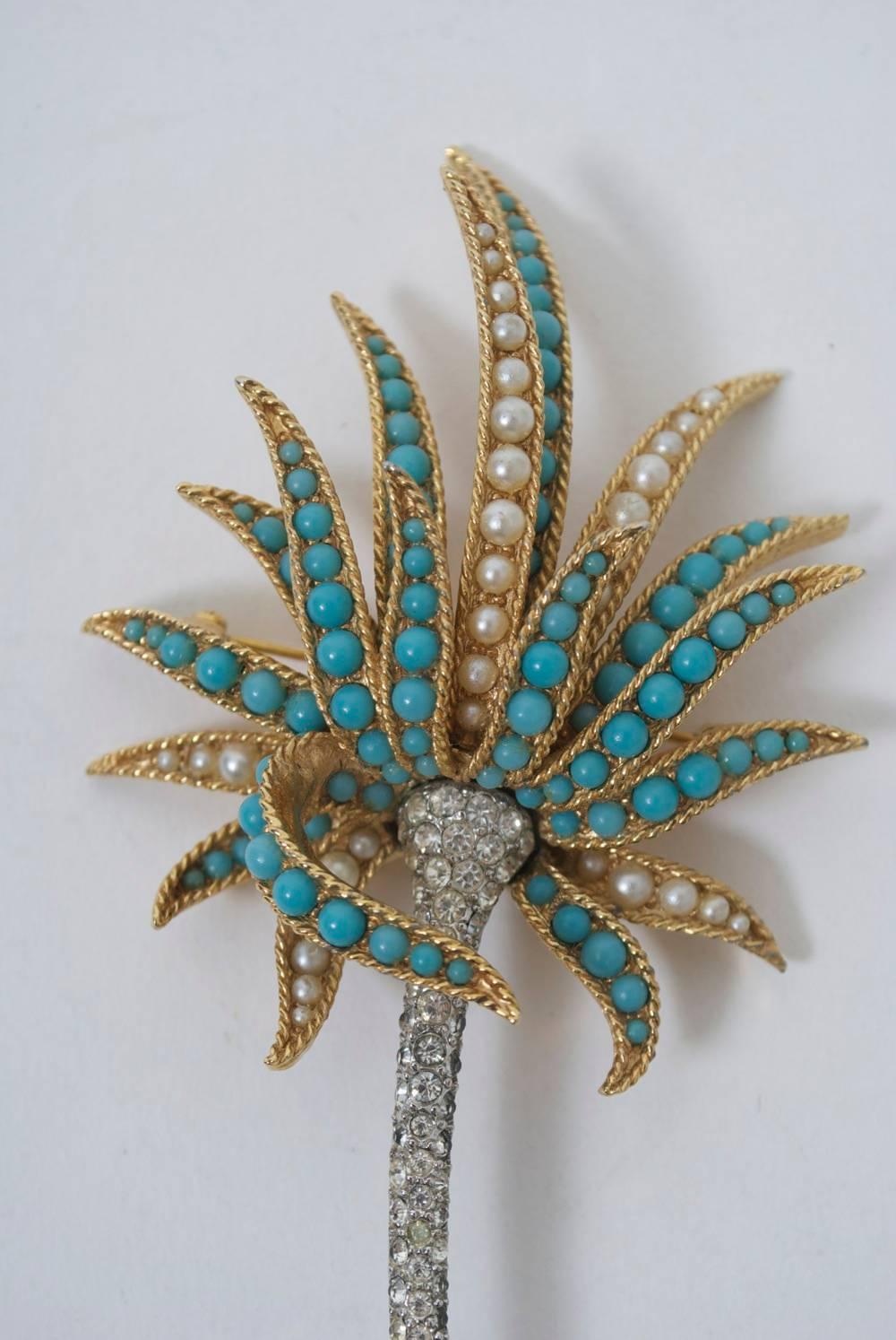 Boucher mid-twentieth century brooch in the shape of a palm, the slender stem composed of rhinestones and the fronds of turquoise stones or pearls. The three-dimensional setting is in gold tone metal with a rope design. Signed and numbered, the