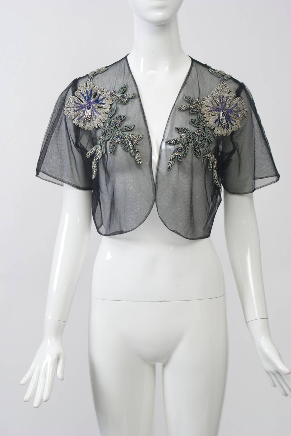 Black net bolero embellished with large beaded floral bursts and leaves. Collarless with short sleeves. Approximate size 8.