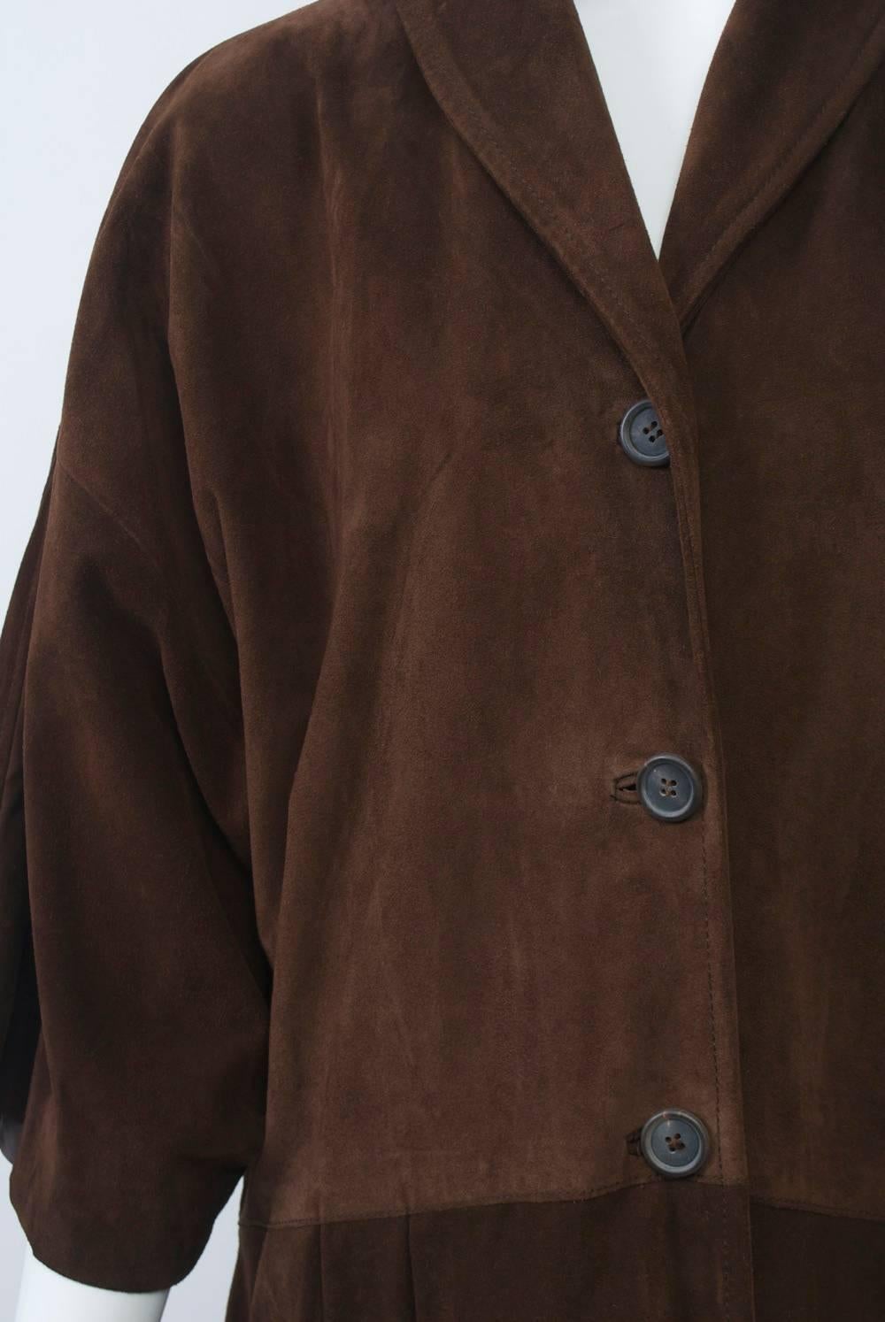 Miu Miu brown suede coat, single breasted, featuring a shallow shawl collar and dropped shoulders with wide three-quarter sleeves. Seaming at the hips above a  skirt with widely spaced pleats. Bound buttonholes. Labeled size L, but more like a size