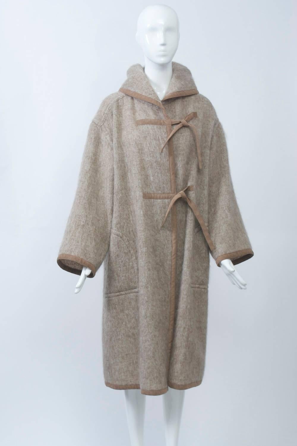 Heather tan mohair coat by Kasper for Joan Leslie featuring ultrasuede trim around edges and as two ties as closures. Dropped shoulder with wide sleeves and collar that converts to a hood. Unlined. Approximate size M.