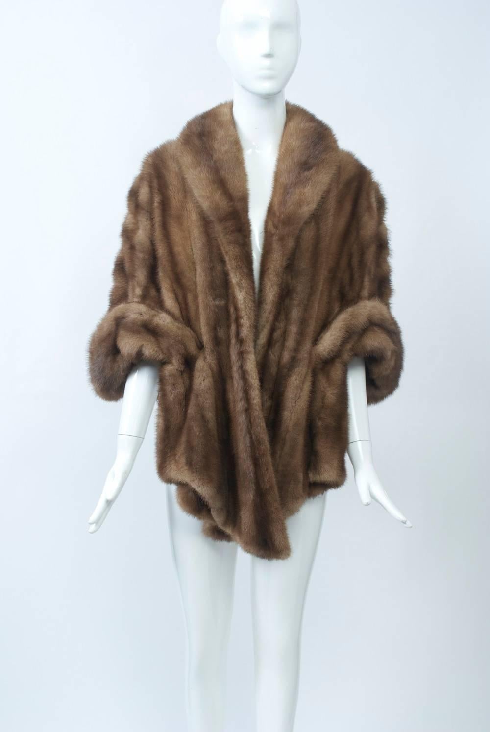 Vintage mink stole in light brown reaches below waist in back, which is seven skins deep. The front features a shawl collar and turned-back cuffs, which make the stole appear like a jacket. Full brocade lining in good condition. A very nice and