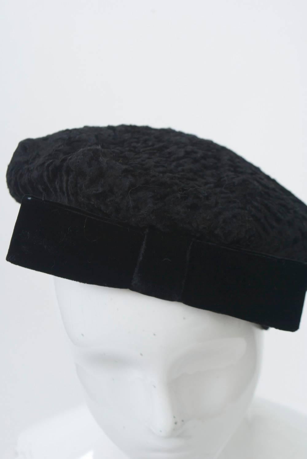 Black broadtail beret trimmed with velvet band and bow. Retailed by Bonwit Teller.