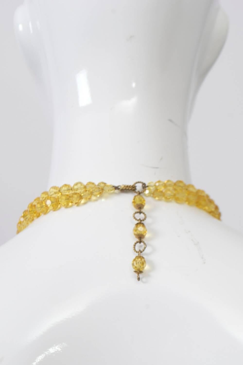 Vibrant crystal beaded choker composed of four strands of faceted round yellow crystals in front and two strands in back, separated by quarter-round spacers covered in two rows of the crystals. Adjustable link and stone closure in back. Marked 
