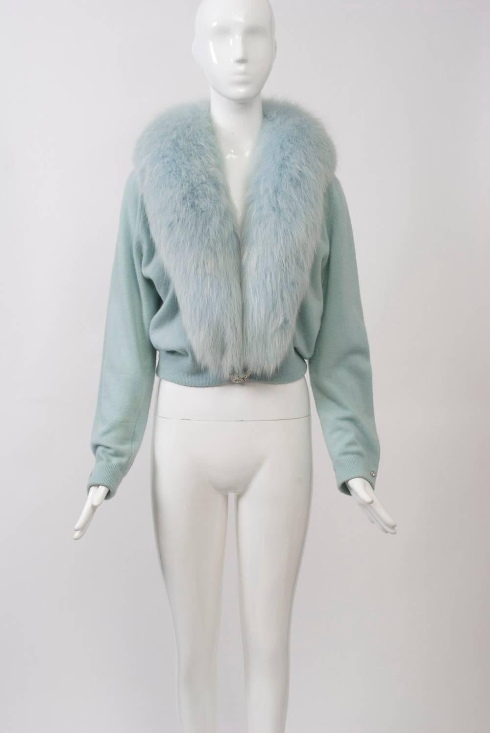 A special example of the decorated and/or fur-trimmed cashmere sweaters that were so popular in the 1950s and '60s, this cardigan is in baby blue with a matching full fox shawl collar. It is further enhanced with a rhinestone clasp at the waist and