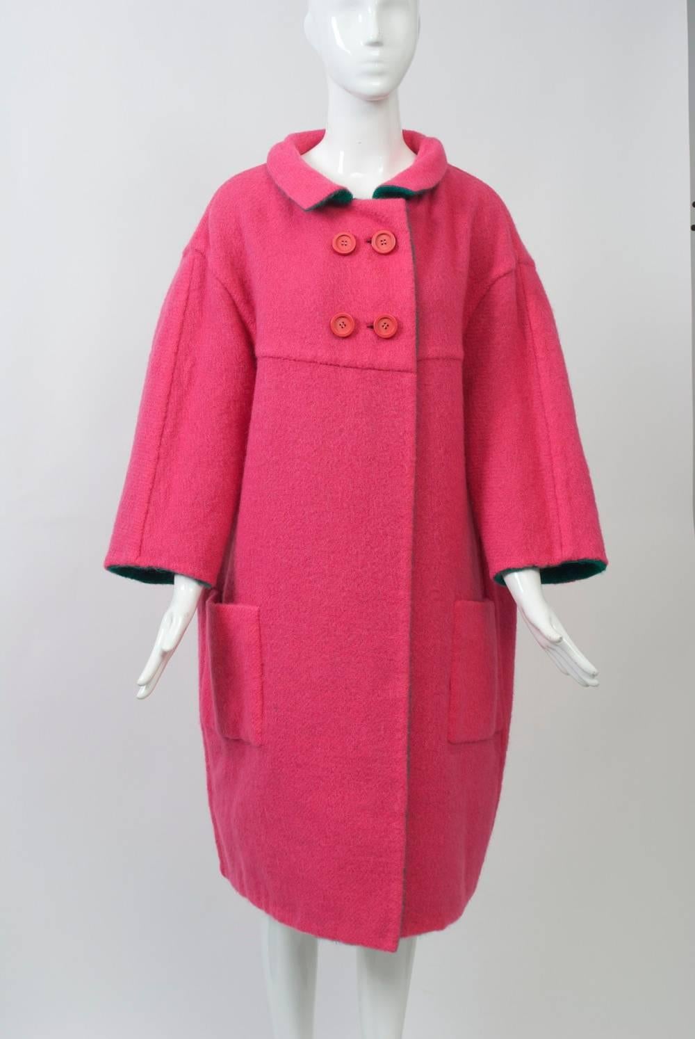 Unique 1960s cocoon-shaped mohair coat reverses from bright green to bright pink. The design features a welted yoke across dropped shoulders, back, and bust, above which are matching double-breasted buttons. Patch pockets, a small collar, and wide,
