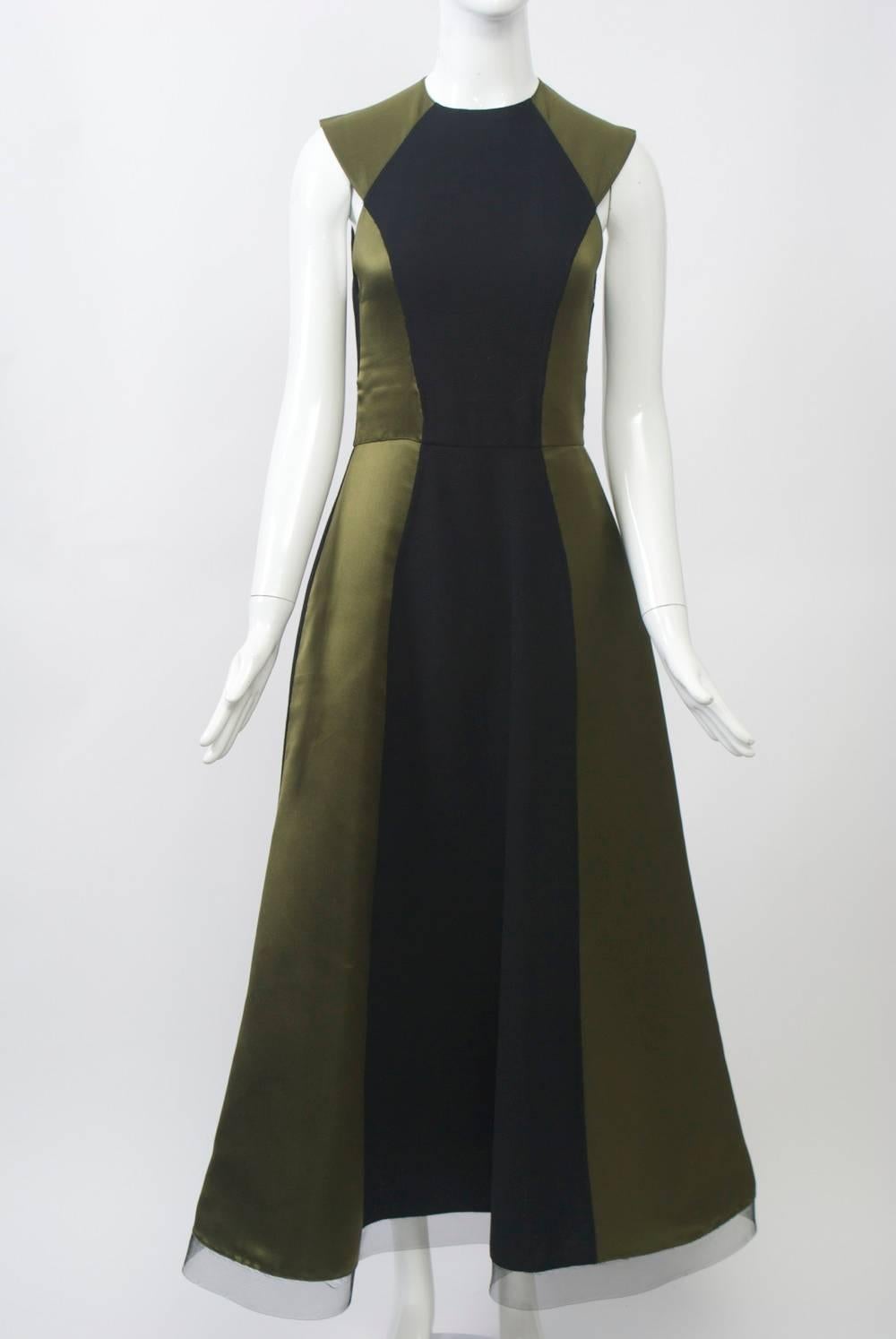 Quintessential Geoffrey Beene in cut and detail, this stunning and sophisticated gown is composed of olive green satin with black wool crepe panels strategically integrated into the design and following the intricate seaming and shape of the dress.