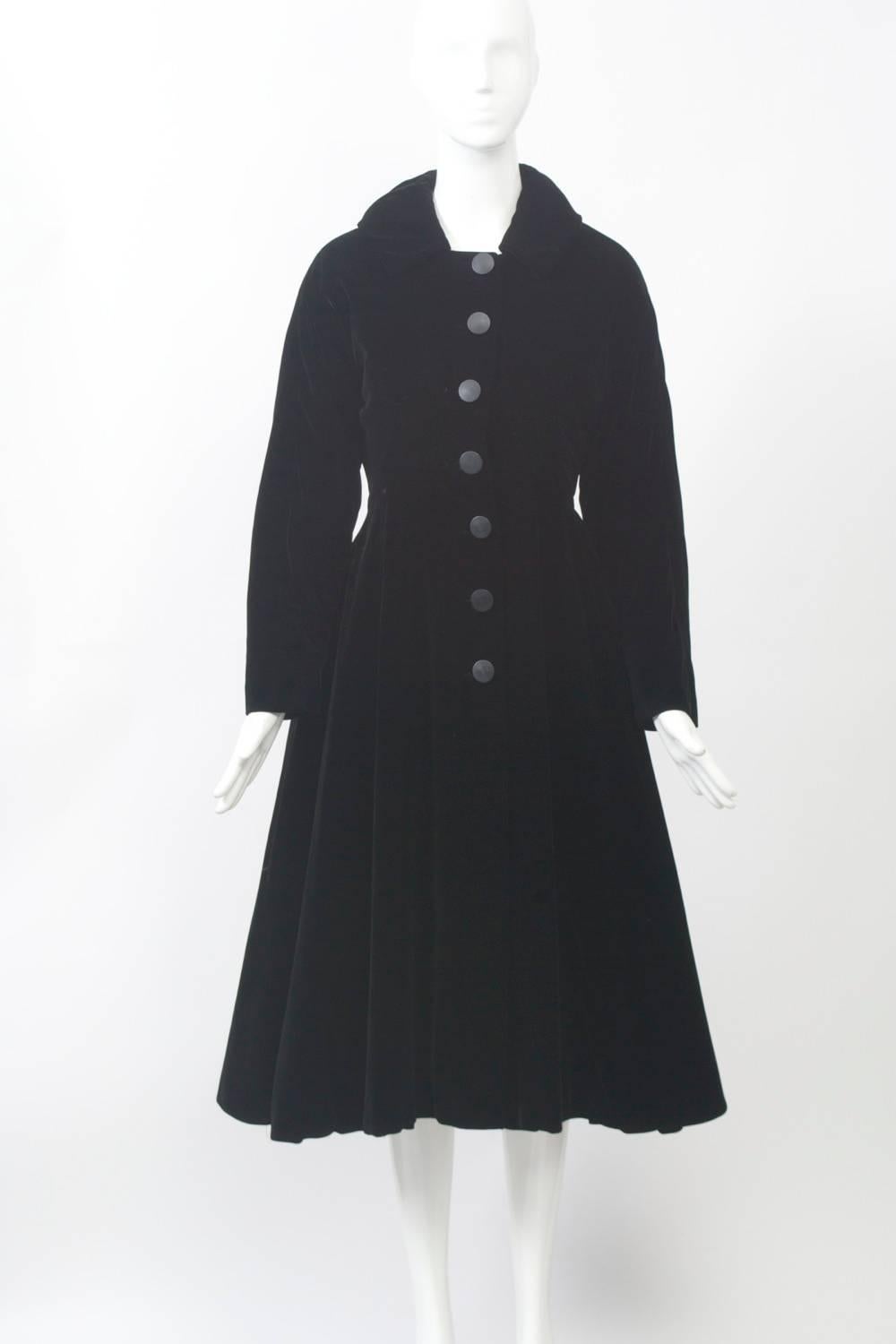 Velvet is in! This black velvet 1950s princess-style coat is in great condition and features a small collar and seven black buttons down the front. The nipped waist and flare skirt so popular during the early 1950s demonstrate the influence of the