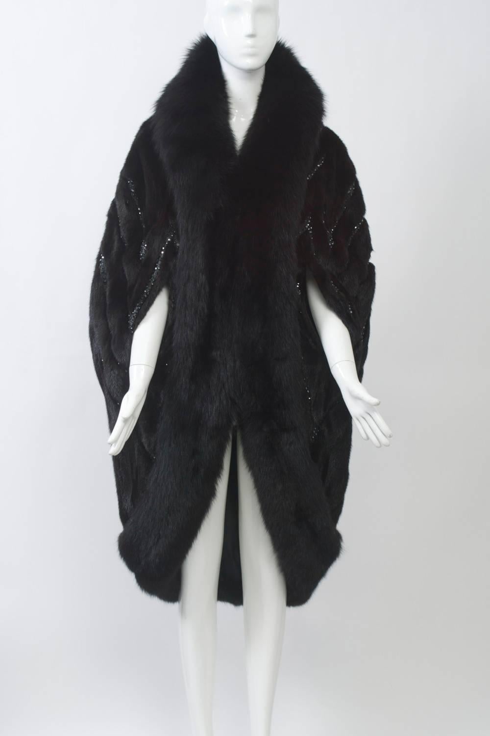 Spectacular fur cocoon cape by Bob Mackie in dark ranch mink trimmed in brown fox. The herringbone-patterned mink features black leather between the mink strips, which is studded with iridescent bezel-set rhinestones. This is a unique, star-quality