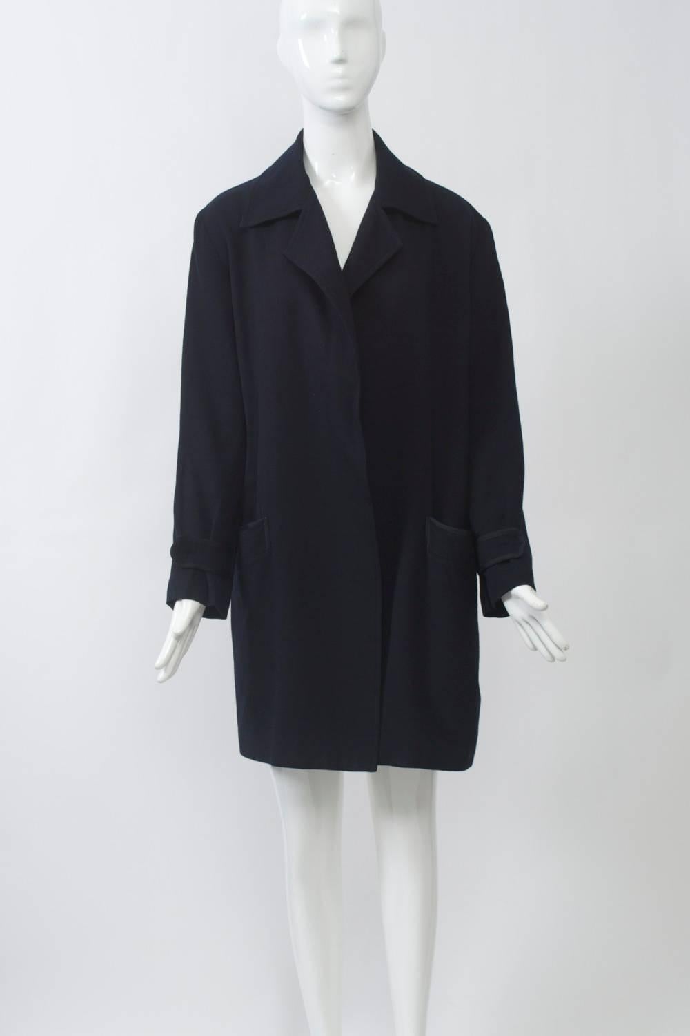 Long jacket in soft navy gabardine that feels like cashmere (the contents label is worn). Notched collar, loose fit, with flat braided trim on pockets and wrist tabs. Yoke back with deep inverted pleat. No closures. Size S-M.