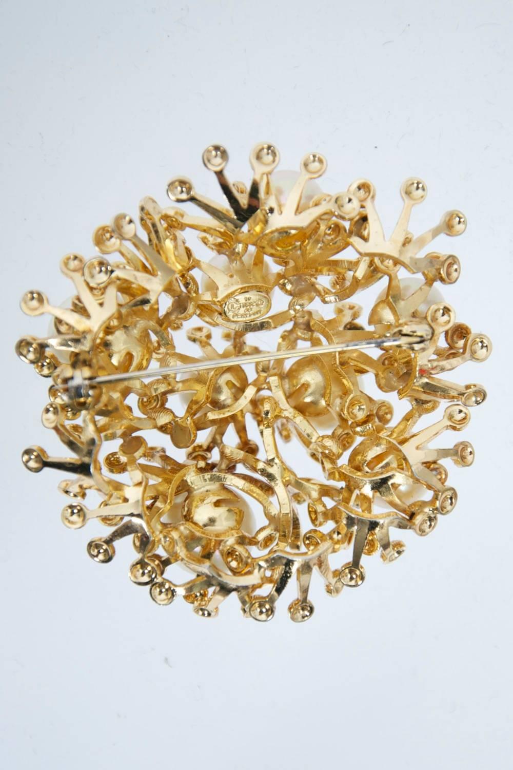 Grosse brooch from 1968 composed of an open network of crownlike elements, each point terminating in a textured drop, and each circular grouping centering a pearl of varying dimensions. Well crafted, as expected of this highly respected German firm,