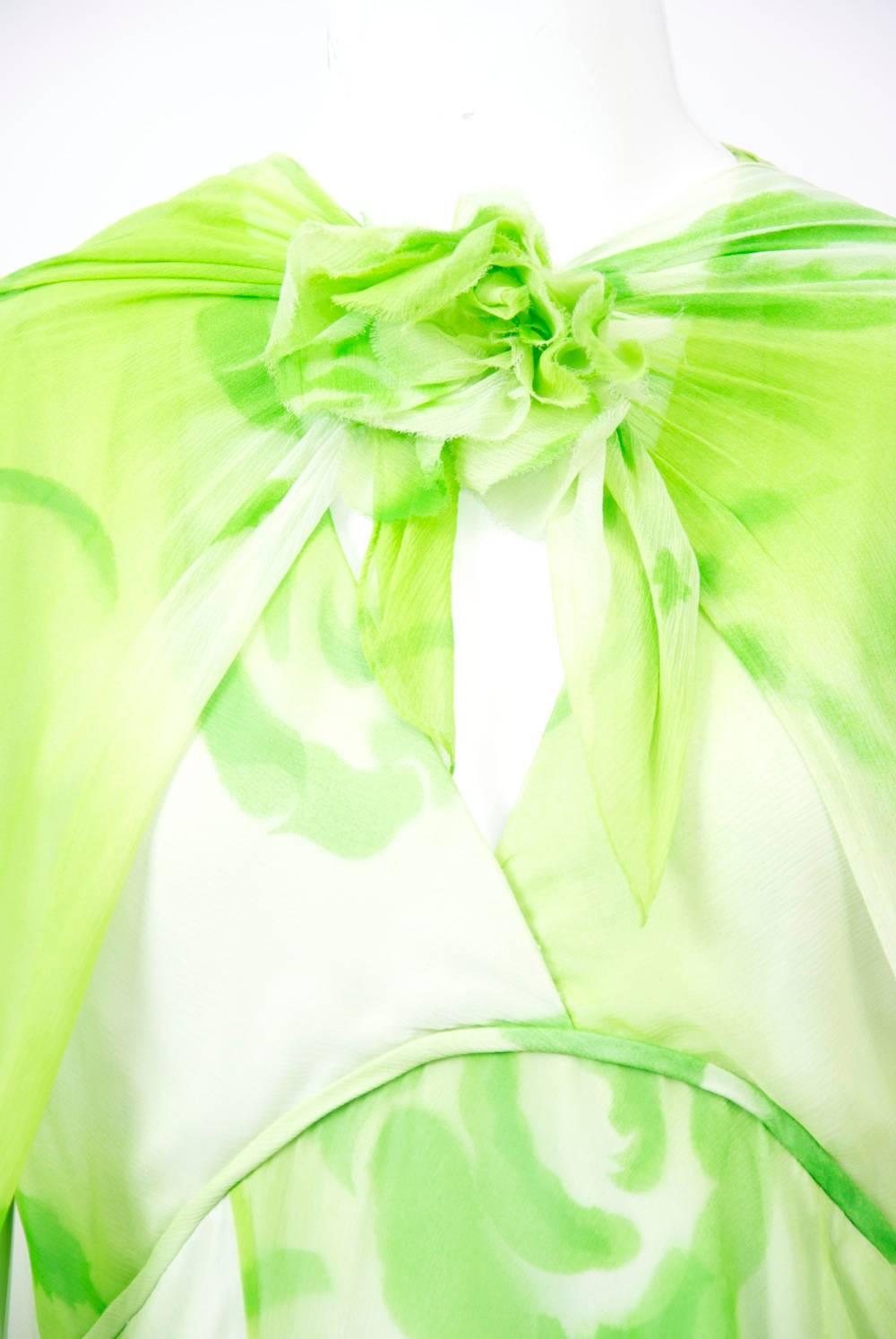 Chiffon gown of watercolor print large-scale flowers in light and dark lime green on an off-white ground. The dress features a v-neck, cut-away armholes in back, and an empire waistline, below which flows the bias cut skirt. Accompanying the dress