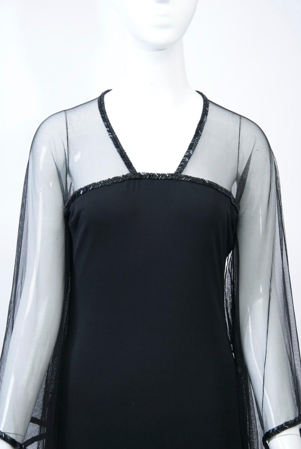 Amy Michelson for Holly Harp 1990s long black dress featuring sheer netting above the bust for the V neckline and raglan bell sleeves, the edges trimmed with a row of black herringbone beads. Below the netting, the black jersey body skims the body.