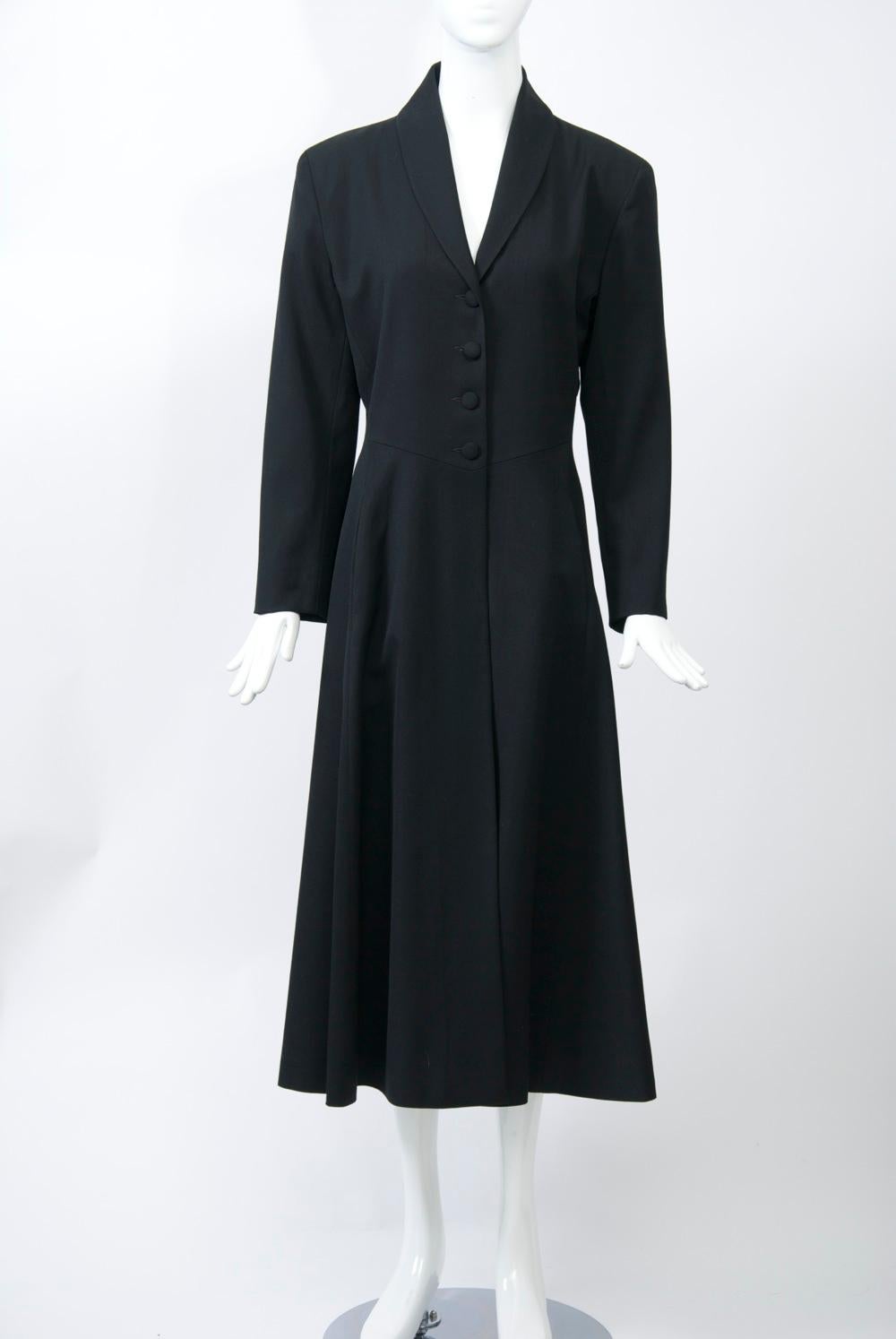 Princess-style coat by Agnes B in lightweight black wool featuring a shallow shawl collar and four self buttons. 1950s retro silhouette with nipped waist and flared skirt. Labeled size 2. Please see measurements below.