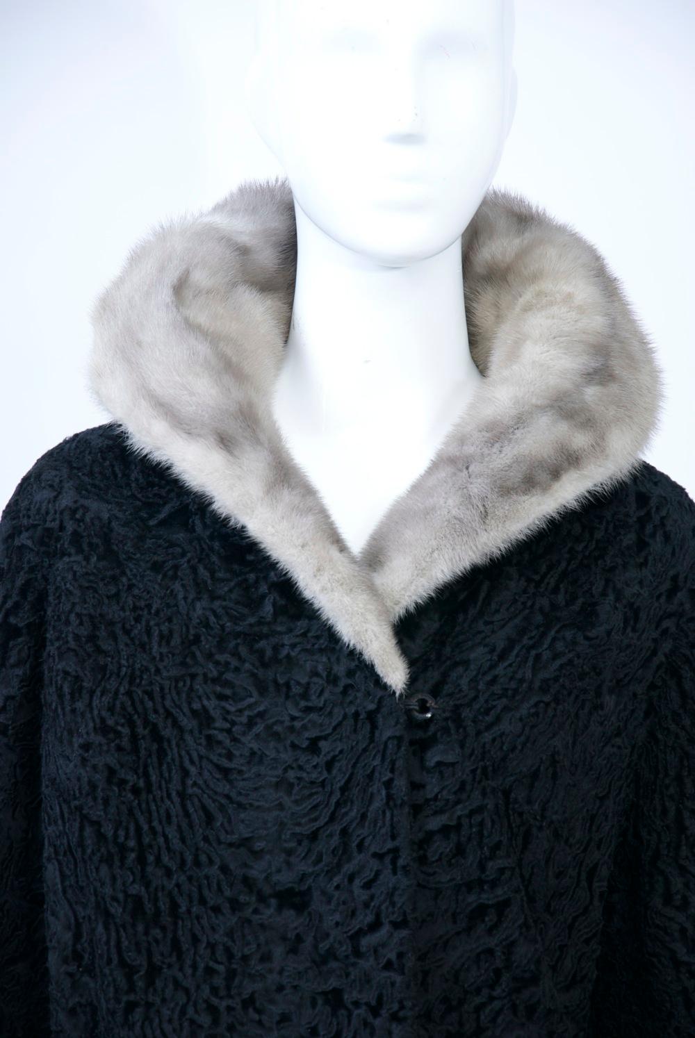 Vintage black broadtail hip-length jacket features a gray mink collar that can either stand up or lie flat and turned-back cuffs. Fur hook closures. Embroidered satin lining.Size S-M.