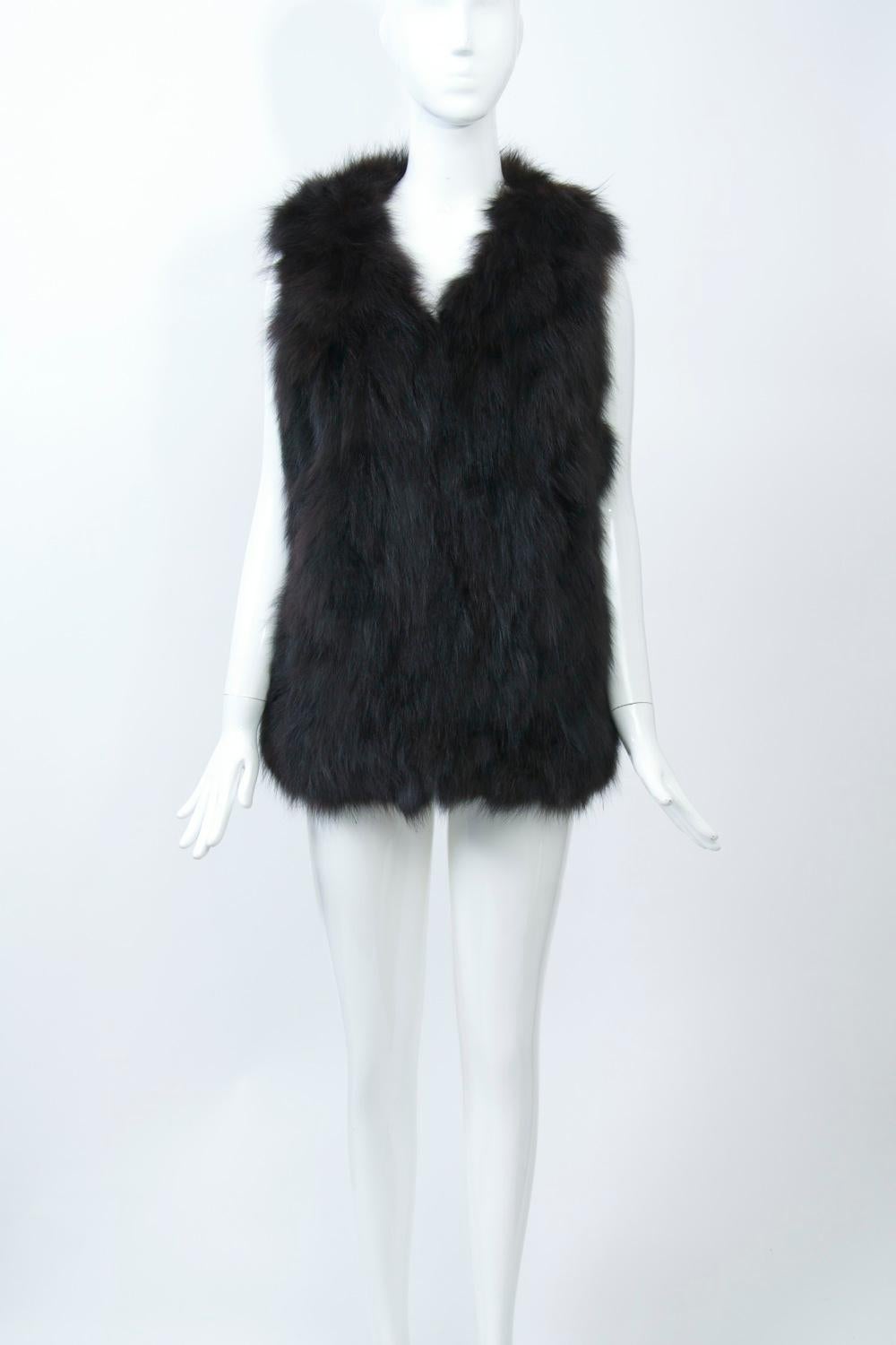 Dark brown pieced fur vest in either dyed fox or opposum with fur-hook closures and featuring a red lining. Easy to wear. Size S.
