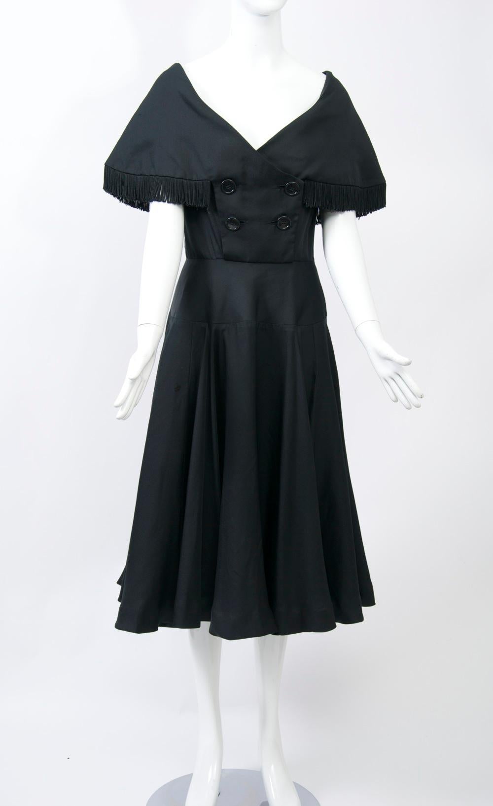 Jacques Fath designed two lines of ready-to-wear per year for NY manufacturer Joseph Halper from 1949 through the mid 1950s. This black dress features some outstanding details, from its fringed cape collar and decolletage neckline to its