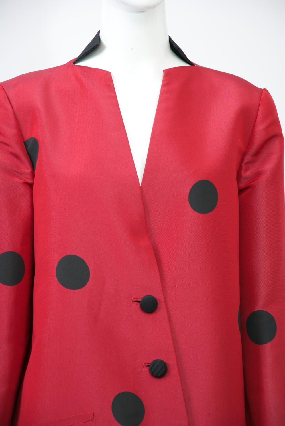 Typical of design master Geoffrey Beene, this suit exhibits the deceptive simplicity and attention to detail for which he was known. The silk jacket is fashioned of deep red silk with large black dots widely interspersed throughout. It has an