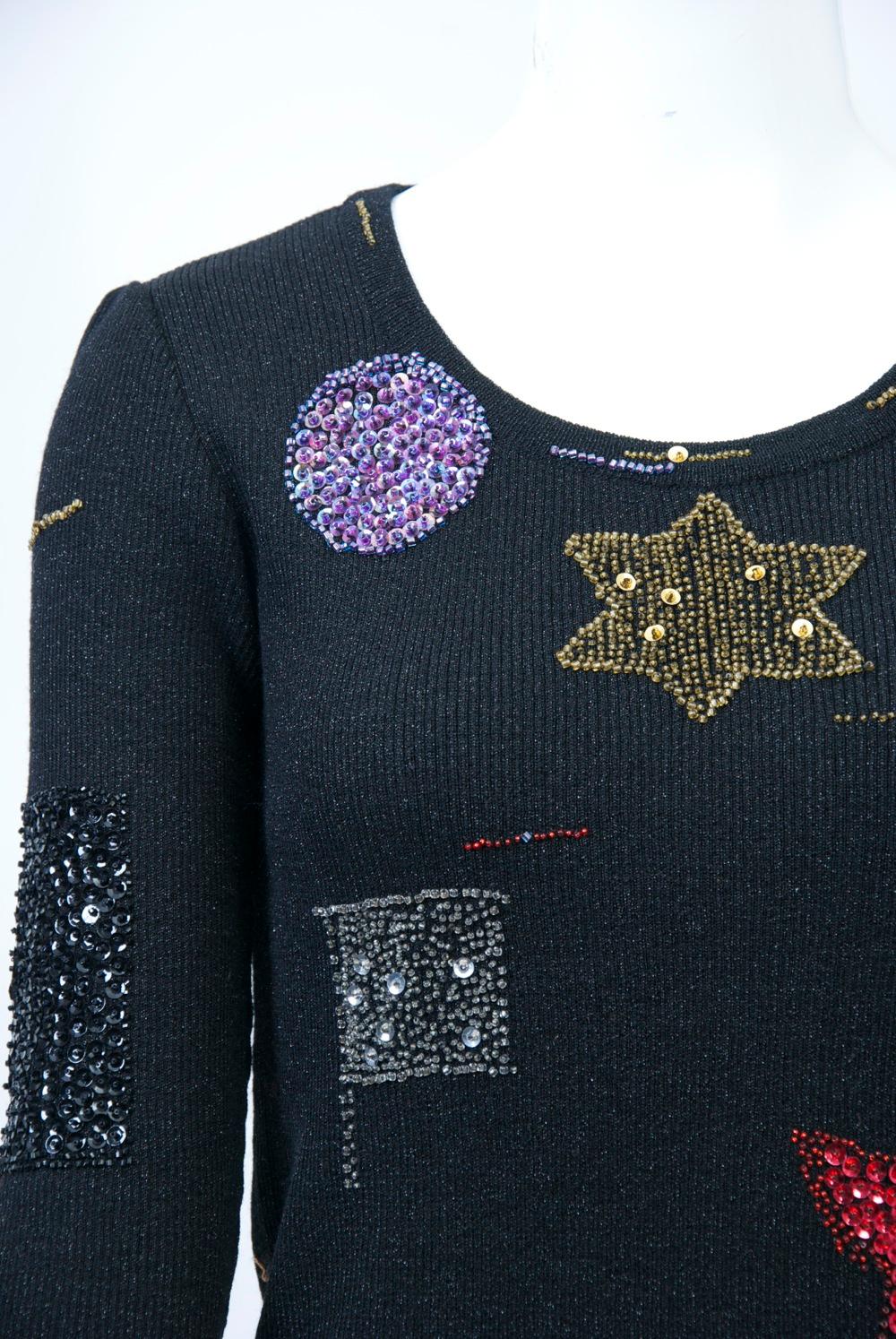 Hanae Mori ribbed black pullover featuring beaded and sequined ornaments of stars, circles, flags, and birds in various colors. Scoop neck, long sleeves. Size M.