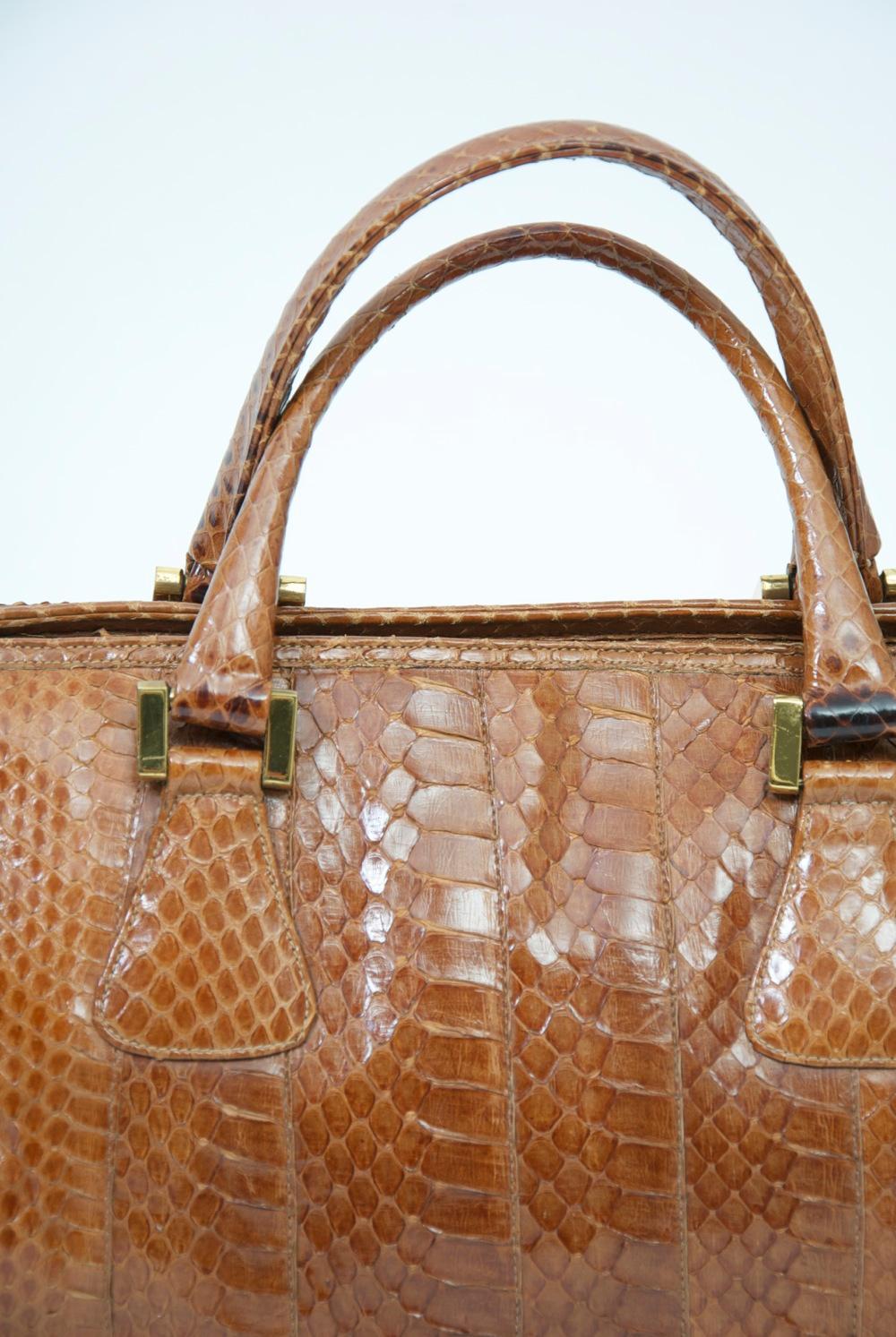 Vintage c.1970s doctor-style handbag in cognac snakeskin by Morris Moskowitz, which produced some of the best bags of the period. Double handles, top zipper with logo pull, metal studs on bottom. Interior with zippered compartment.