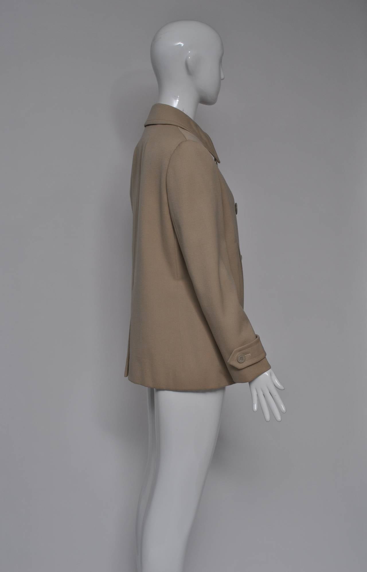 Nicely styled and fashioned Bill Blass pea coat from the 1970s in beige gabardine. Double breasted with nautical-theme buttons, tabs at the wrists and at the neck, and straight, slash pockets. Trim silhouette, print lining. No signs of wear.