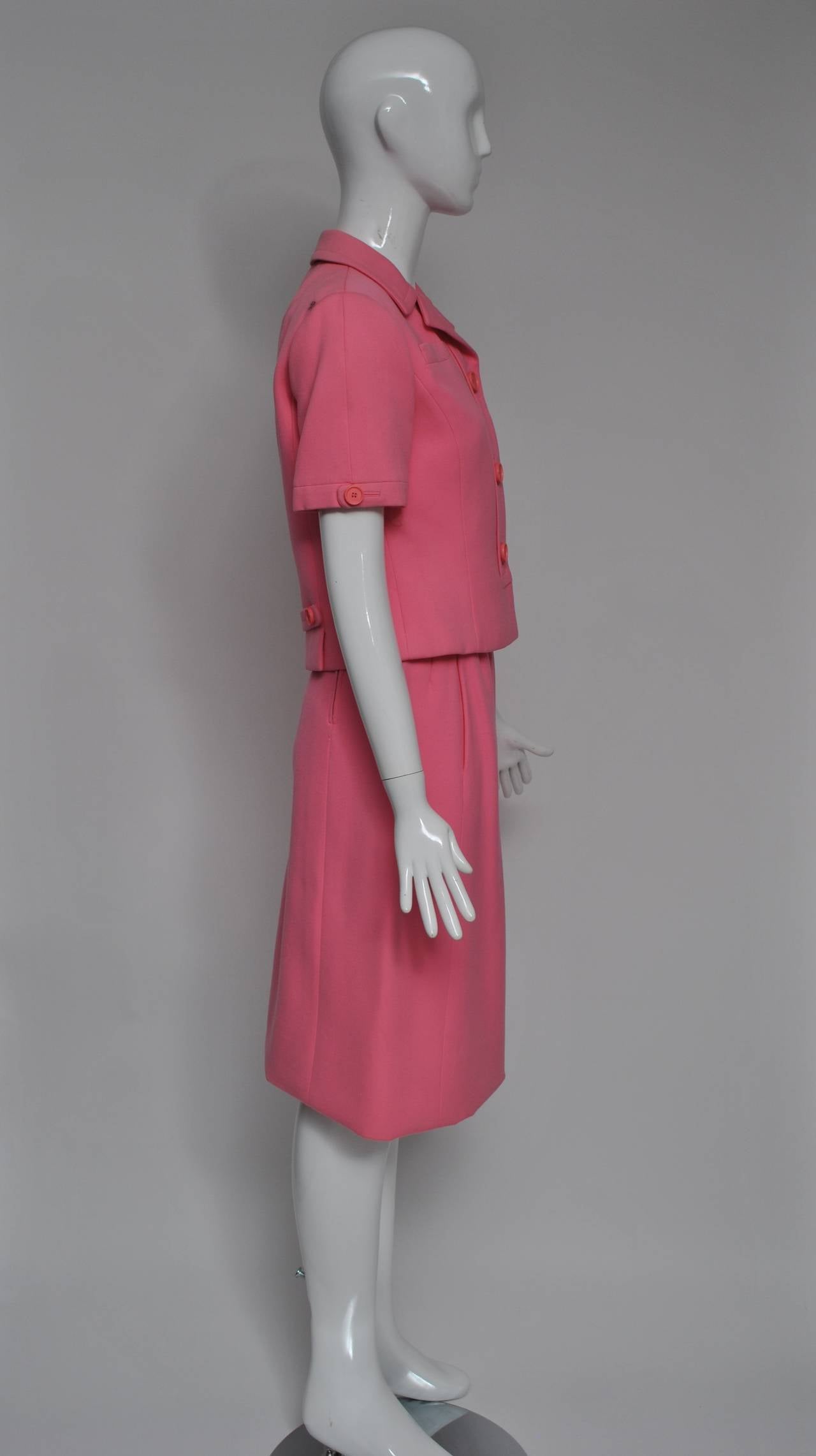 Beautifully tailored suit by Ben Zuckerman, who produced some of the best coats and suits in mid-twentieth-century America. Here is a spring suit from the 1960s in bright pink wool, the jacket with short sleeves, placket detail down the front and