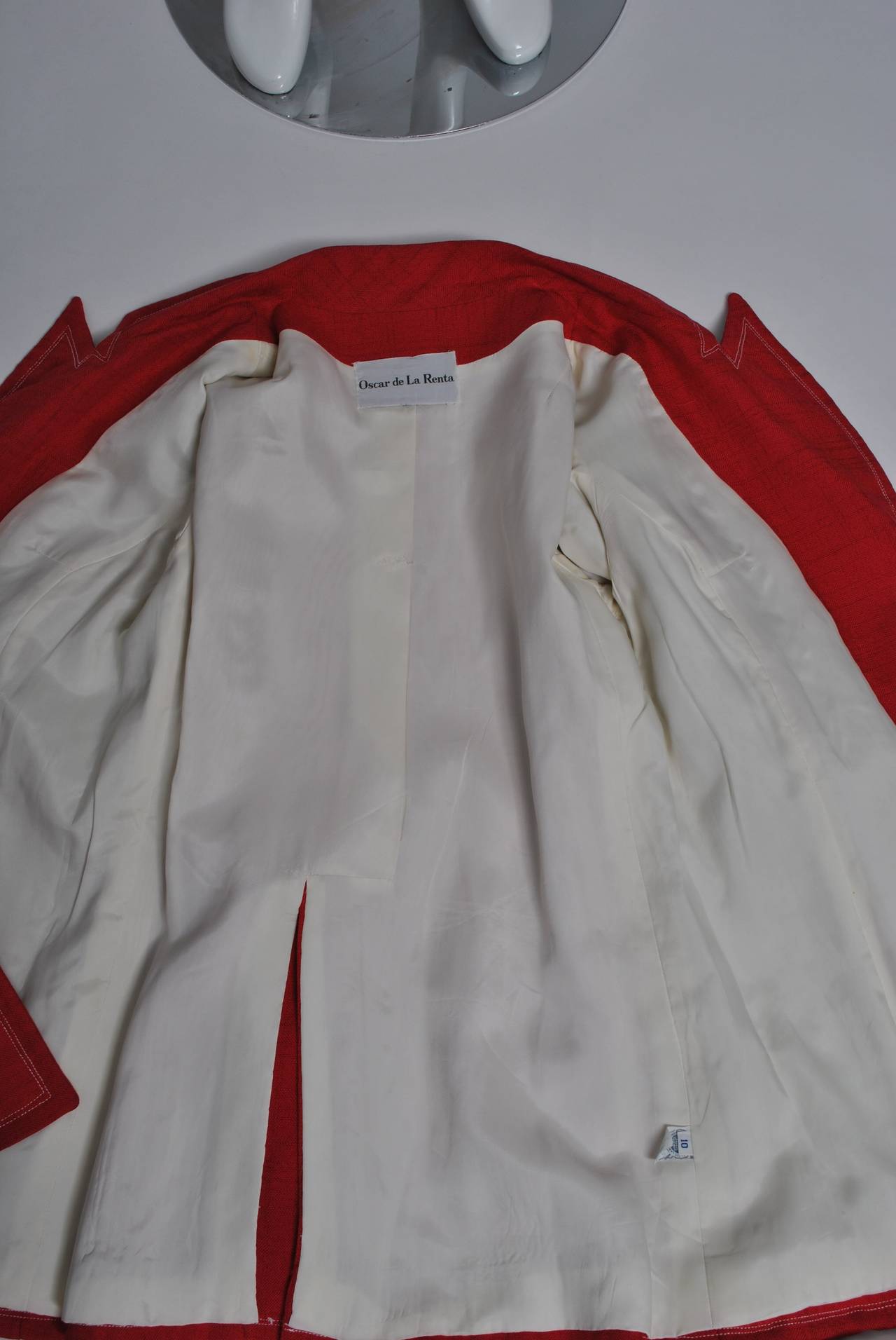 Red linen-like blazer by Oscar de la Renta features white top stitching and buttons, as well as a long, fitted shape and faux flap pockets. Back vent. Lined in white.
