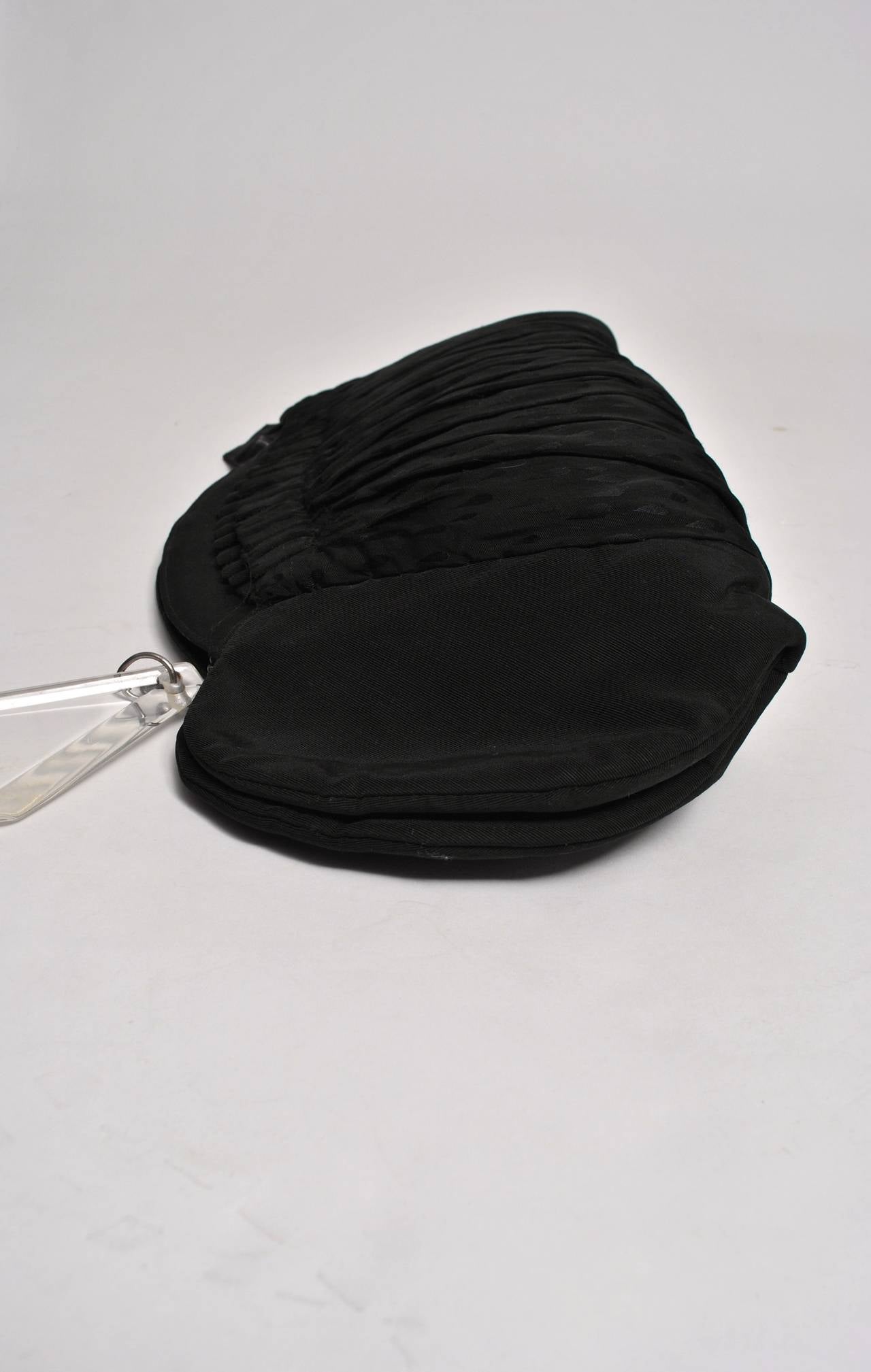 A unique design from the 1940s, this oversized clutch in black faille features a curved top and sides as well as central section of black-on-black design fabric that matches the trim on the gloves. Most likely a custom design, the clutch also boasts