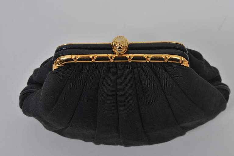 Chanel Black silk faille evening bag converts from a clutch to a shoulder bag with a long chain strap. Softly pleated shape with gold tone frame and ball clasp incised with Xs; gold chain has same markings. Leather interior with side zip