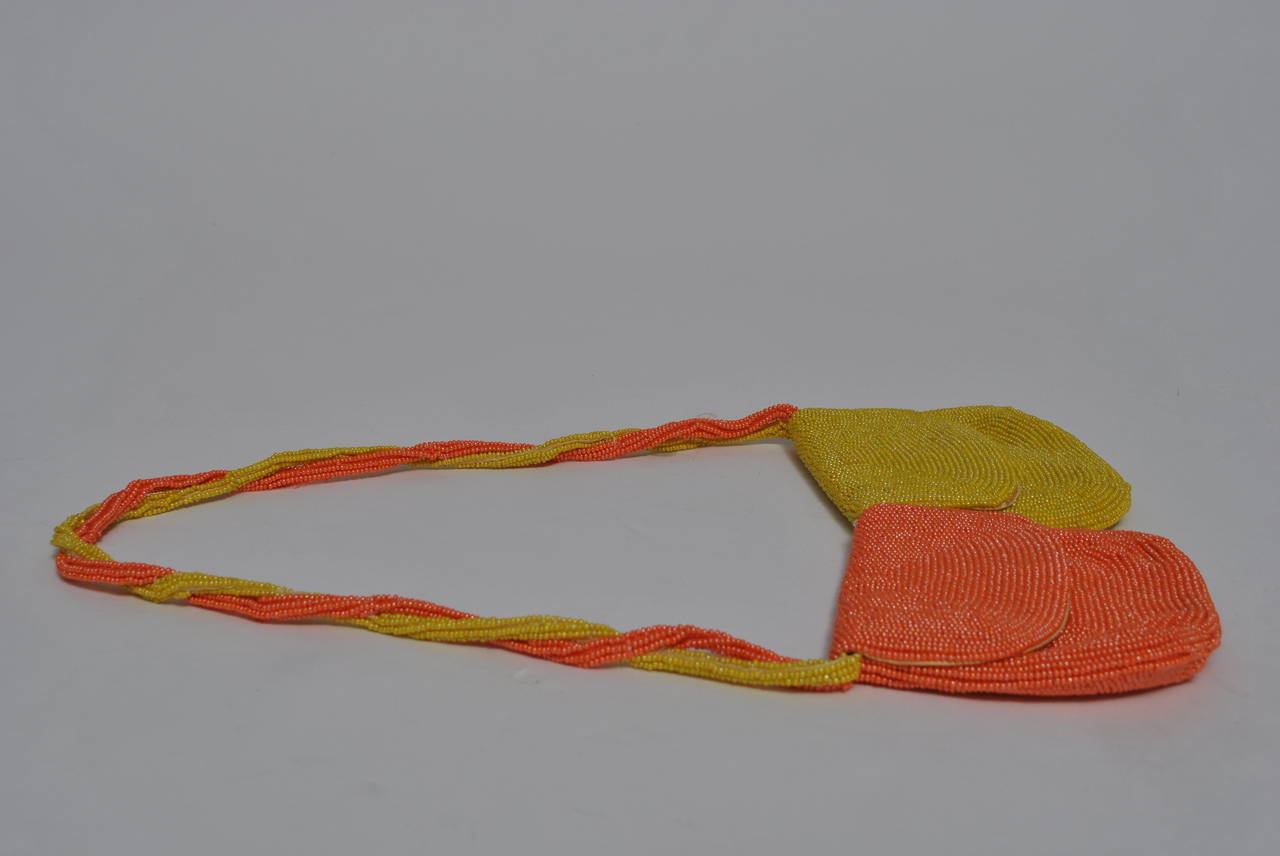 Unusual beaded double pouch bag, half orange, half yellow, with twisted strap. White satin lining. Snap closures. Made in Japan for Walborg, a major producer of beaded handbags during the mid twentieth century.