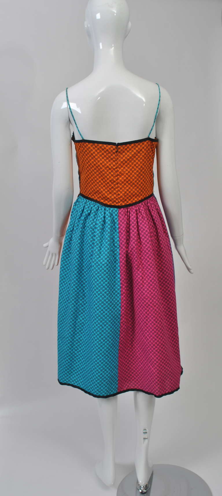 Enjoy the warm weather in this color block sundress from the 1960s-'70s featuring a small black floral repeat on turquoise, orange, purple, and pink sections. Spaghetti-strap bodice and gathered skirt, all borders bound in black trim. Bodice is