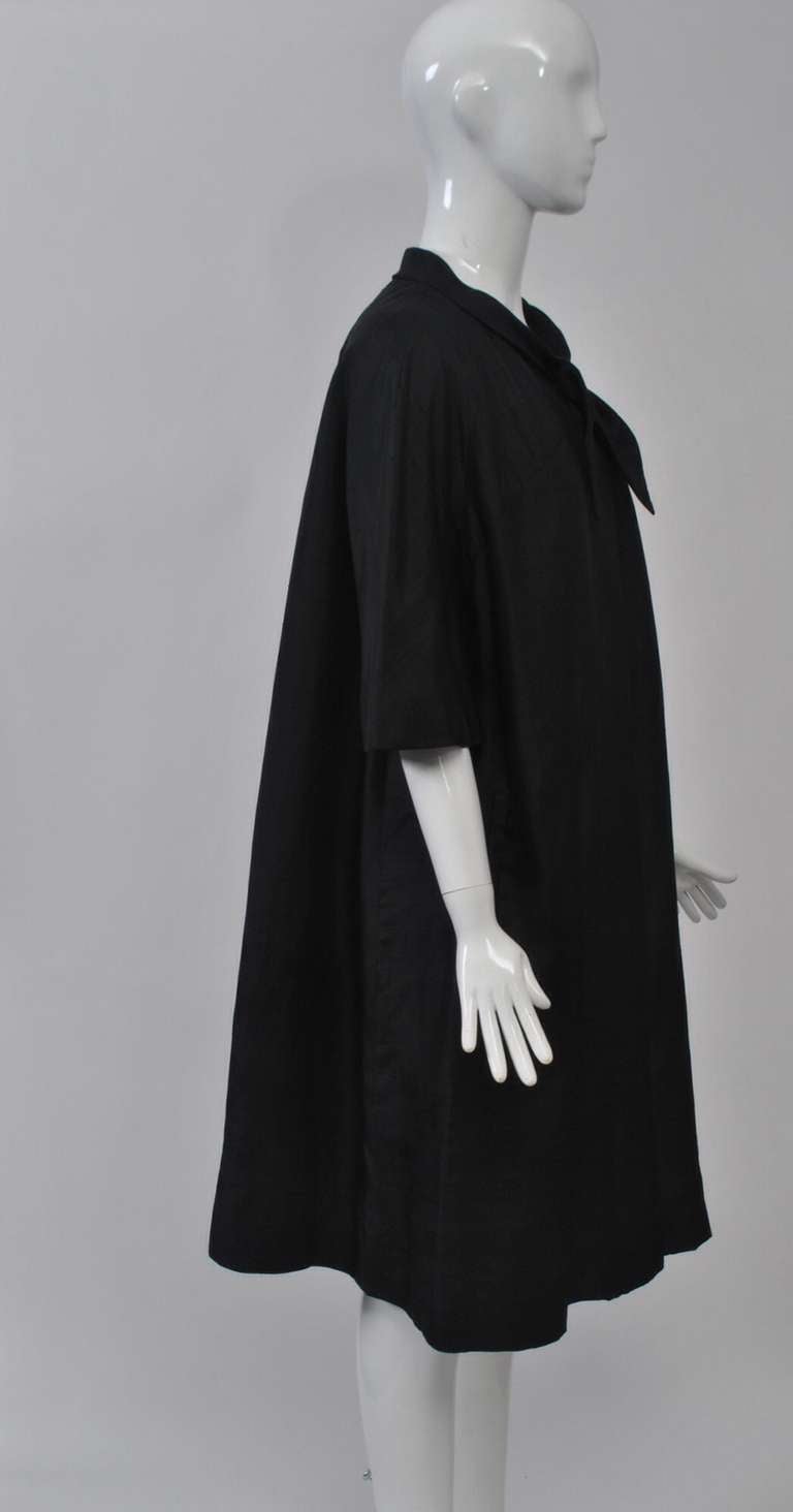I am always searching for this type of lightweight coat from the 1950s and '60s, as they are great staples to have in your wardrobe. This version, in black silk, features elbow-length sleeves, a tie neckline, and a loose silhouette. Always chic and