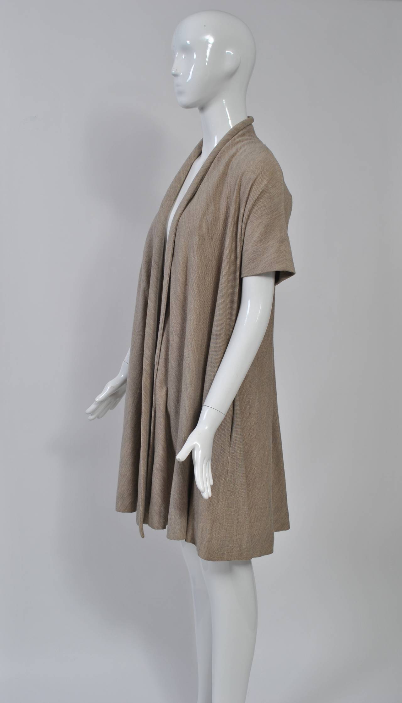 Claire McCardell short-sleeve swing coat in oatmeal wool knit features raglan sleeves, side pockets and rolled collar edge. Unlined. Very wearable with a contemporary wardrobe. Size S.