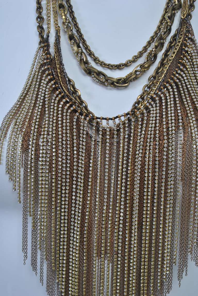 Una collana di Rodrigo Otazu del 2010, noto per le sue stravaganti creazioni per Madonna, Lady Gaga e per il cast di Sex and the City. Realizzata con più strati di catene d'oro e cristalli Swarovski e chiusa da una fibbia in pelle e ottone, la