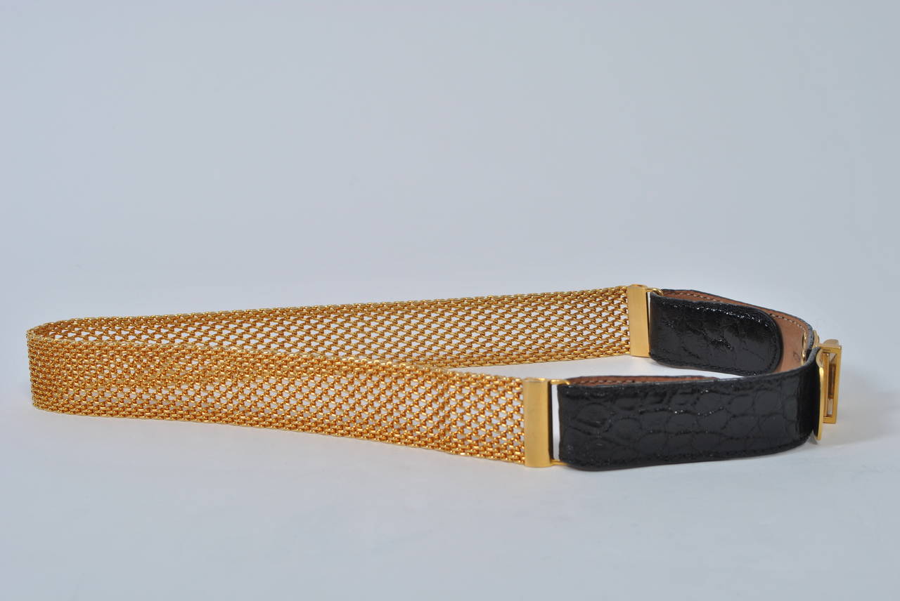 A wonderful accessory to complement your wardrobe, this belt consists of gold metal mesh and black alligator, the firm gold mesh encircling the back of the waist and the alligator in front. It closes with gold metal hardware with a slide catch. Very