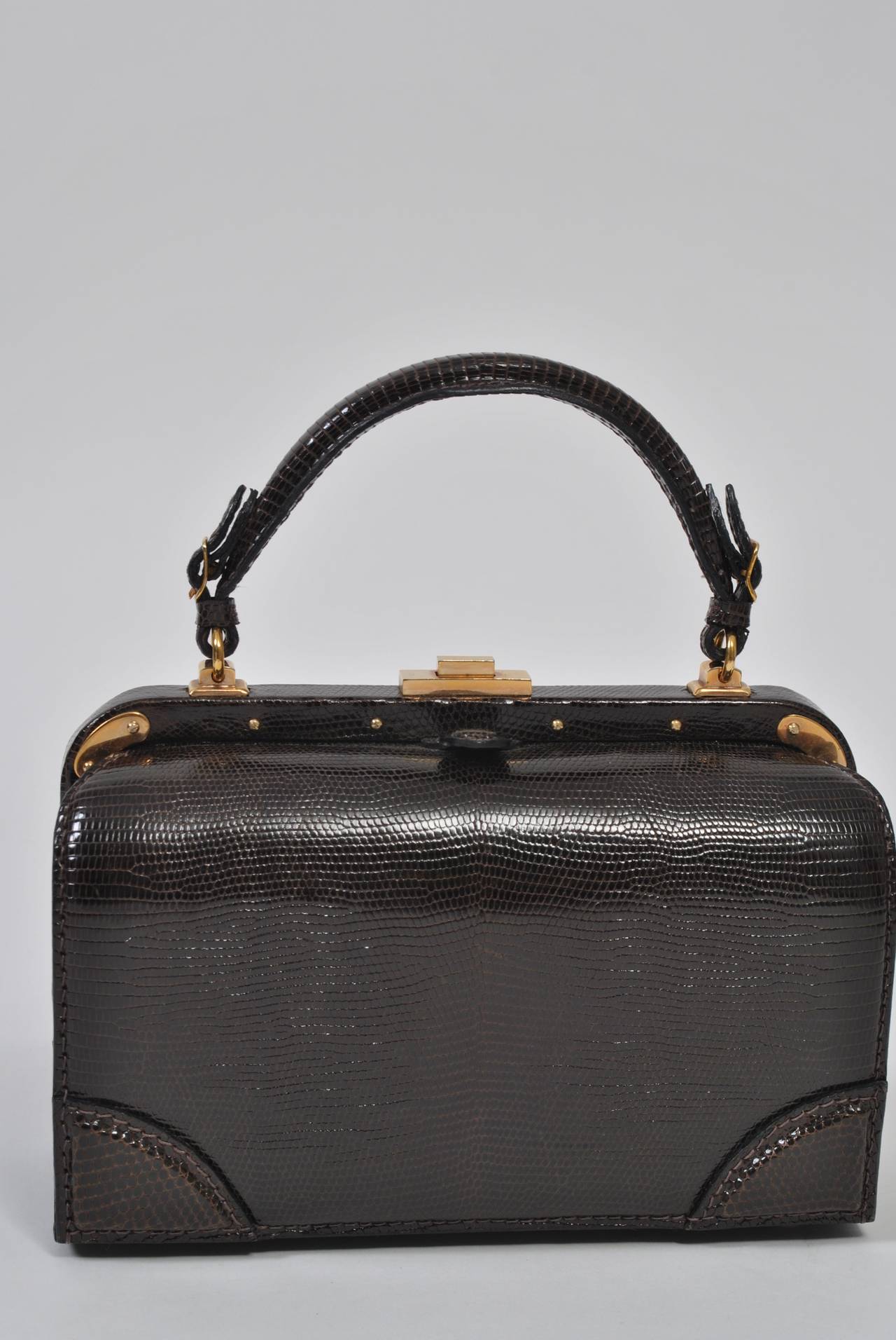 From high-end leather goods purveyor Lederer, this private-label 1960s handbag is crafted in France of brown lizard and features distinctive gold metal hardware throughout. The rounded box shape is classic mid century and is in mint condition. Press