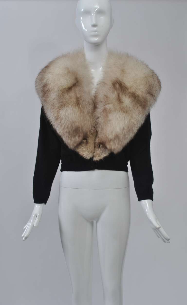 Fur-trimmed and decorated cardigans were must-haves during the 1950s and '60s. This is one of the best examples of the former variety, with its oversized, sumptuous fox collar. The cashmere cardigan has black satin uttons at waist and wrist. The