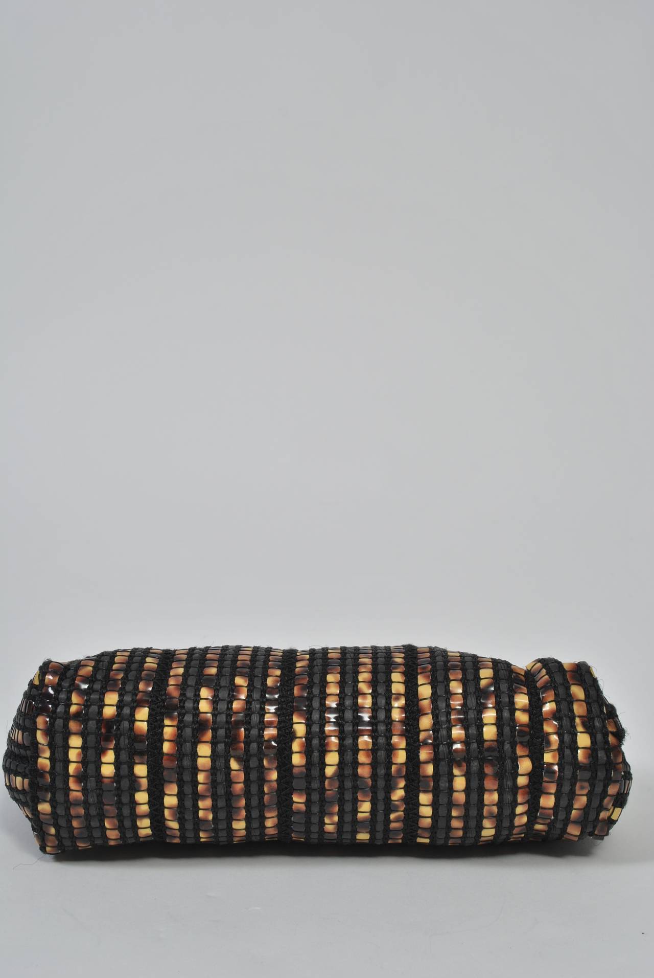 1970s clutch woven of mottled plastic strips resembling tortoise and with a plastic tortoise kiss frame. Interior is black taffeta. Made in Italy. These clutches were very popular during the 1970s, but this is a particularly interesting and unusual