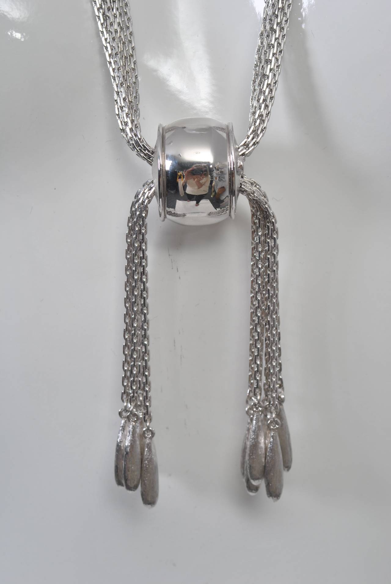 Long Monet necklace composed of multi strands of silver chain caught in the middle with a polished silver barrel and terminating with silver tassels at the ends. slide the barrel to achieve different looks. Back clasp.